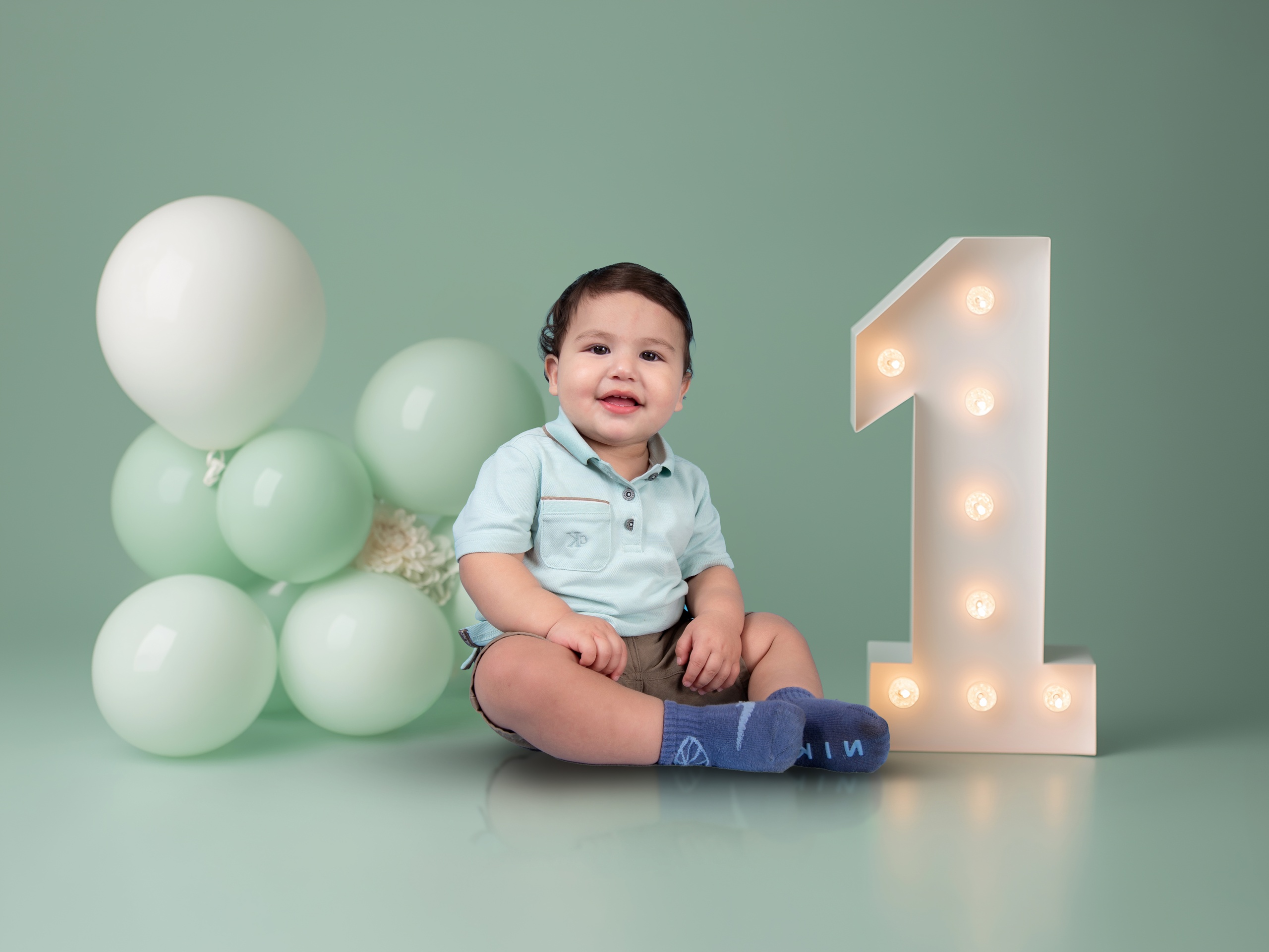 First birthday portrait with green balloons